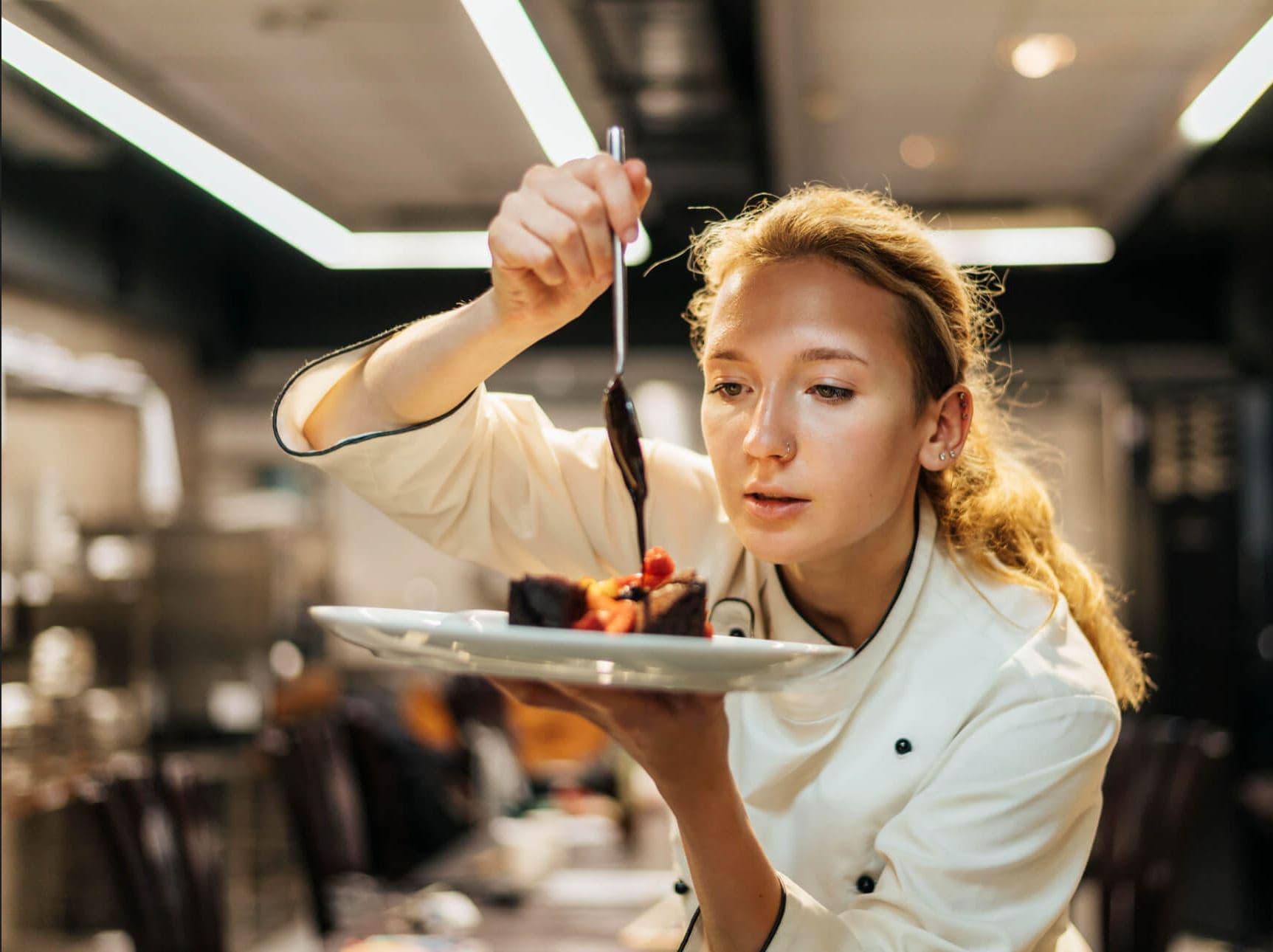 A chef finishes a dessert plate in a restaurant kitchen.