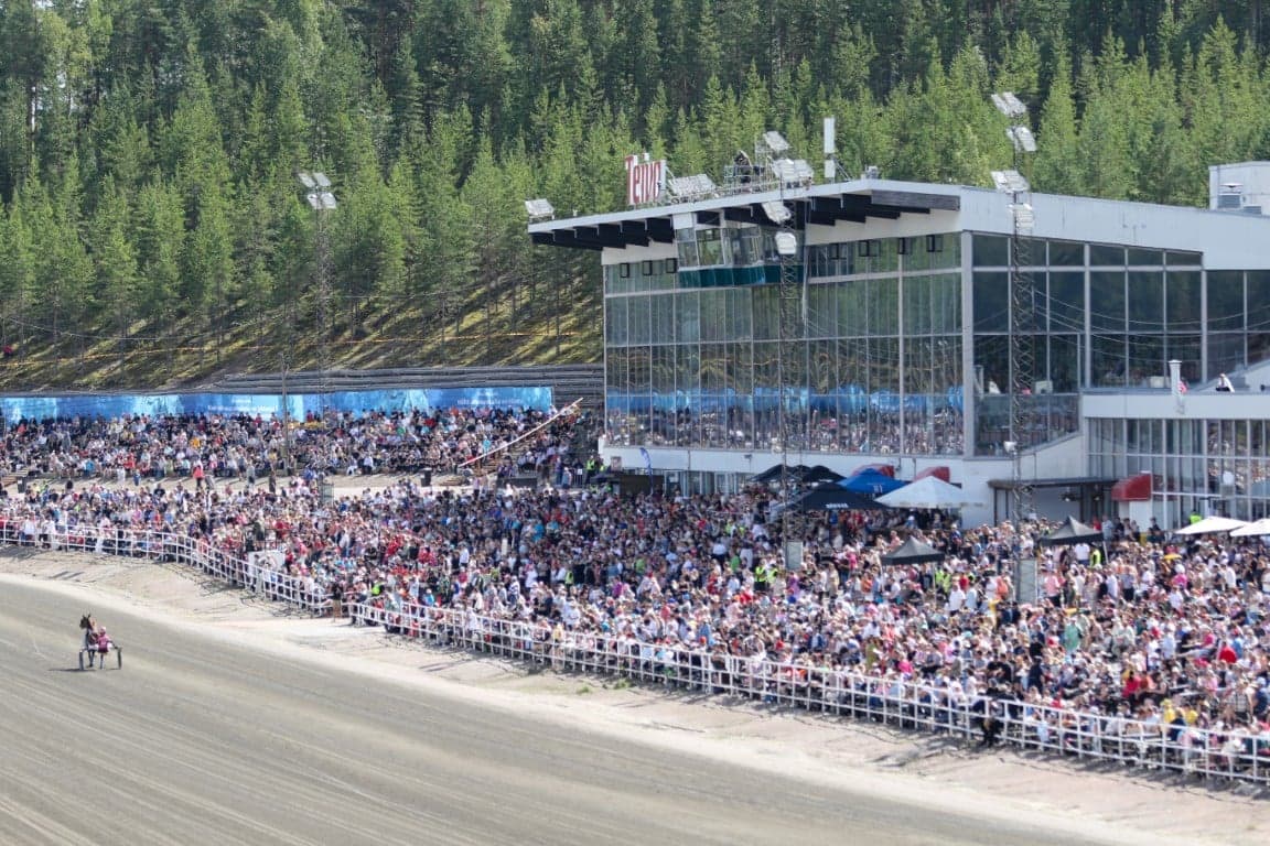 Suuri yleisö istuu ja seisoo katsomossa radan vieressä.